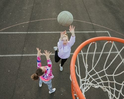 Girls Playing Netball On Clean Hard Court